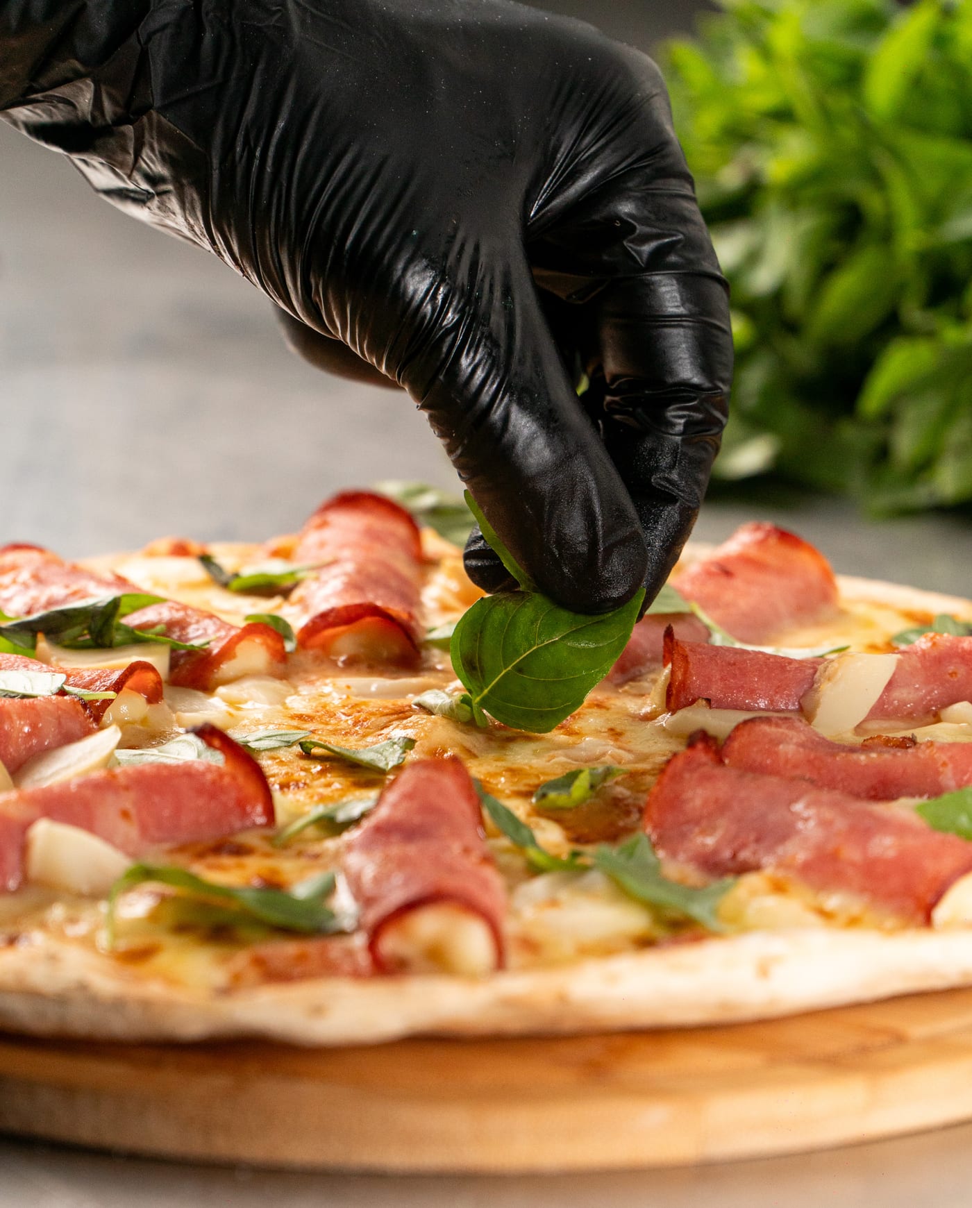 Pizza artesanal Øliver's · mão finalizando com manjericão fresco