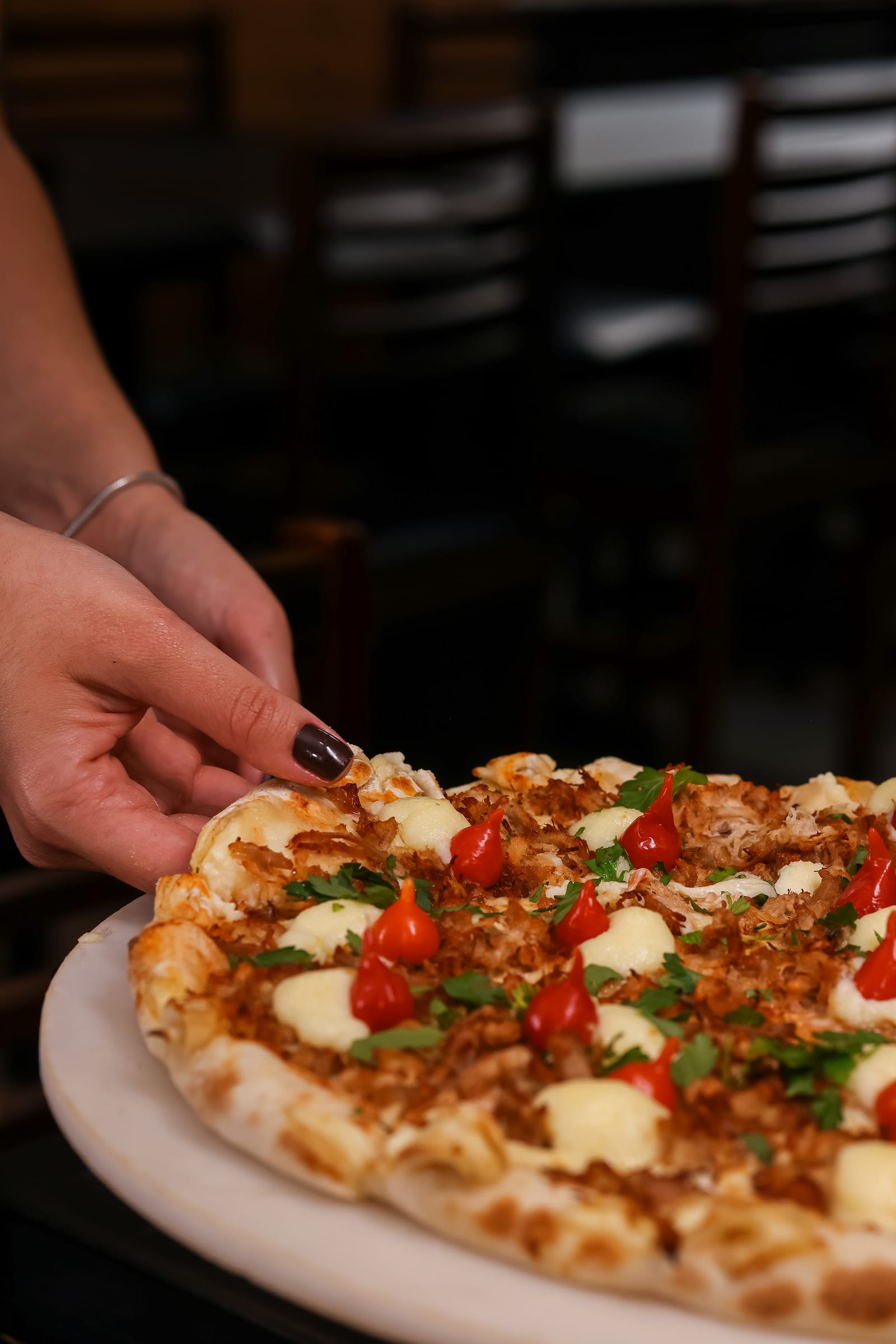 Fatia de pizza Øliver's sendo puxada com queijo derretido escorrendo